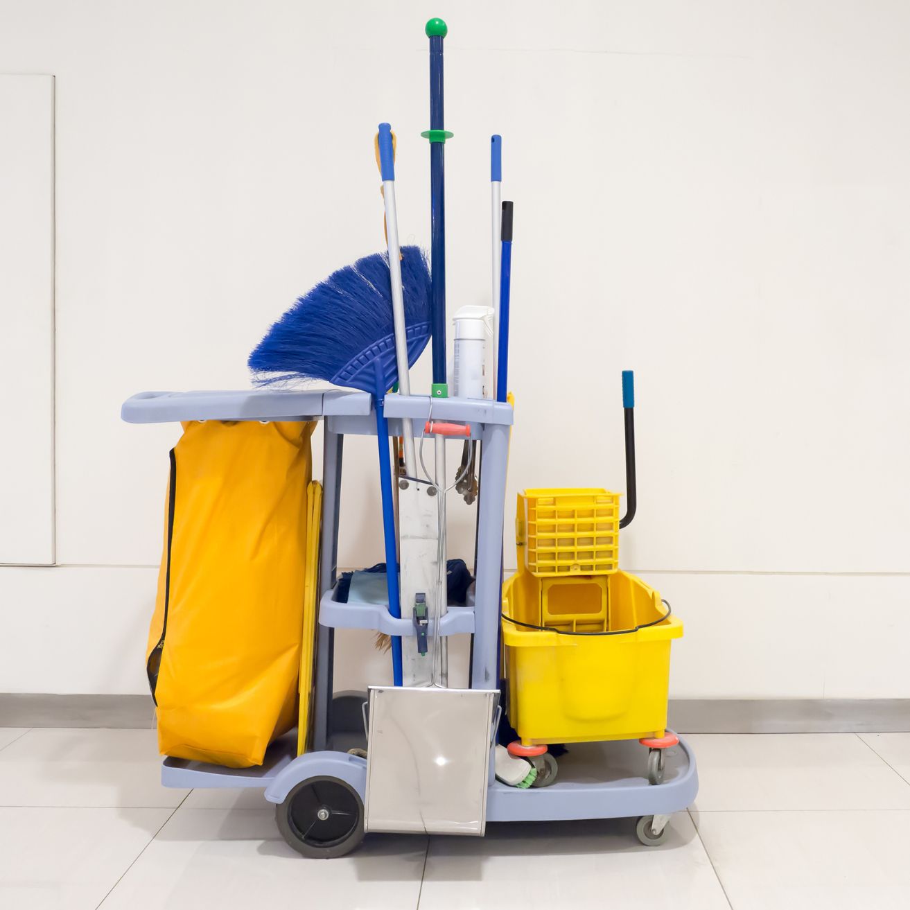 Assorted janitorial supplies including mop, bucket, spray bottles, detergent, gloves, and paper towels used for commercial cleaning